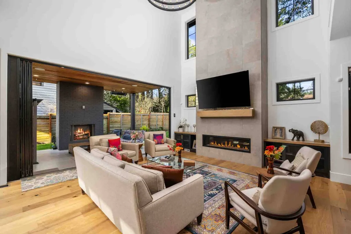 A spacious, open living area with a comfortable sofa set arranged around a modern fireplace and a large TV. Decorative accents and expansive windows create a warm, inviting environment perfect for movie nights and group relaxation.