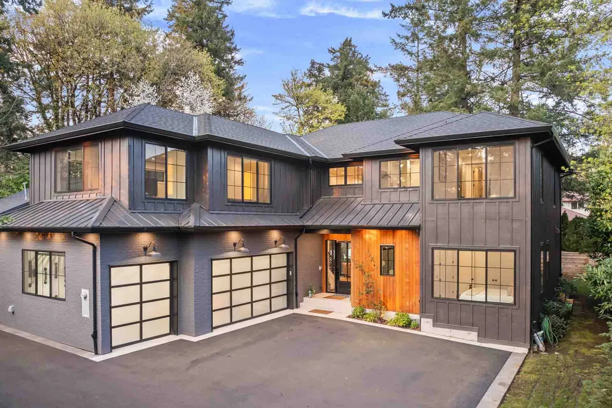 A modern home exterior with a welcoming entrance, wooden front door, large windows, and professionally landscaped greenery. The ambiance is inviting and upscale, highlighting curb appeal and neighborhood quality.