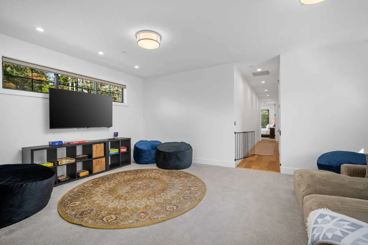 An inviting media room setup with a comfortable sofa, bean bags, and a television on a shelving unit. The cozy setting is ideal for watching movies or relaxing, with ample space for a sleeper sofa or rollaway bed.
