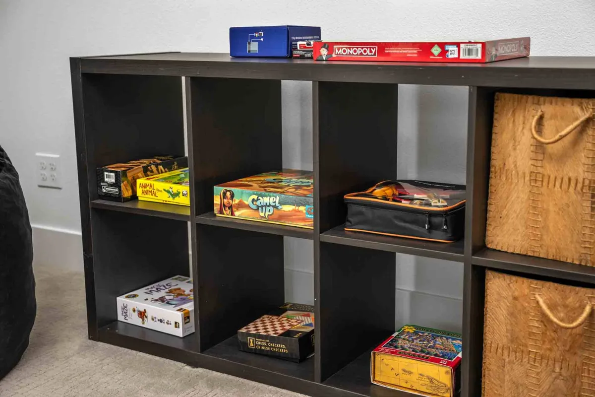 A close-up of board games and storage baskets, signaling the playful side of the house and encouraging friendly competition among guests. The arrangement is casual, inviting everyone to join in for an evening of games and laughter.