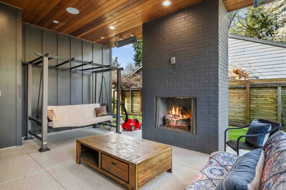 A cozy lounge area centered around a fireplace, with a unique swing seating option, a wooden coffee table, and patterned decorative chairs. The setup exudes a comfortable, social atmosphere, ideal for informal gatherings and unwinding after a productive day.